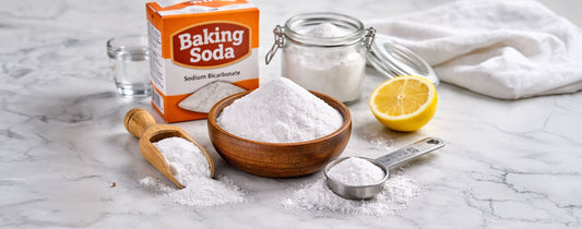 Sodium bicarbonate, most commonly known as baking soda, is displayed on a marble table with a scoop and a lemon wedge